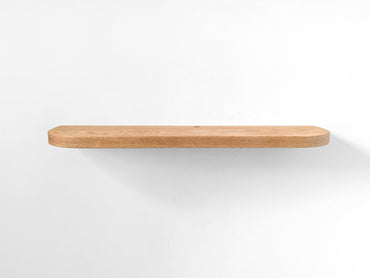 Straight photo of a thick oak floating shelf with curved edges and a cord hole