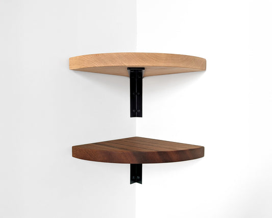 Two rounded corner shelves with metal powder coated black metal brackets are attached to the corner of a wall.