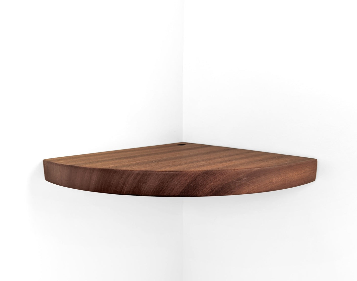 Mahogany corner shelf with grommet hole is installed on a white wall.