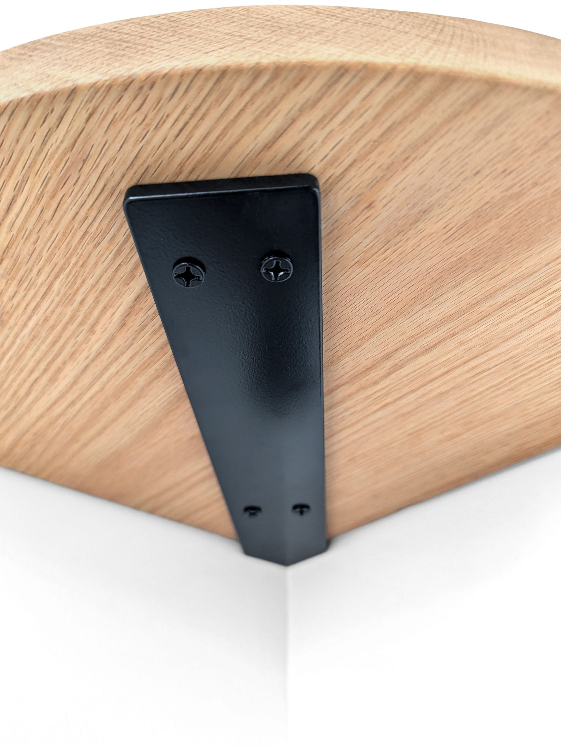 Underside of an oak corner shelf with a black metal bracket.
