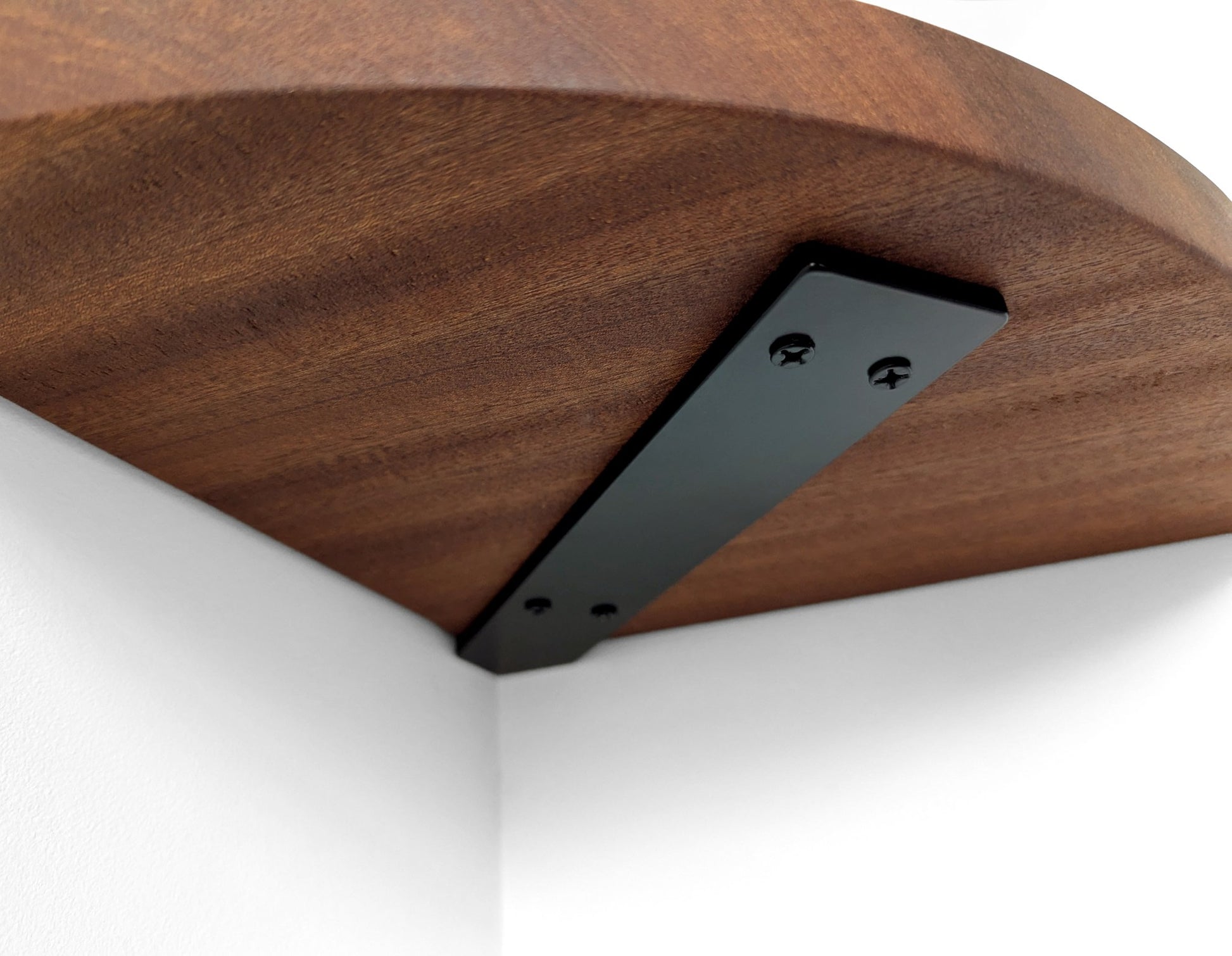 Underside of a mahogany corner shelf with black metal bracket.