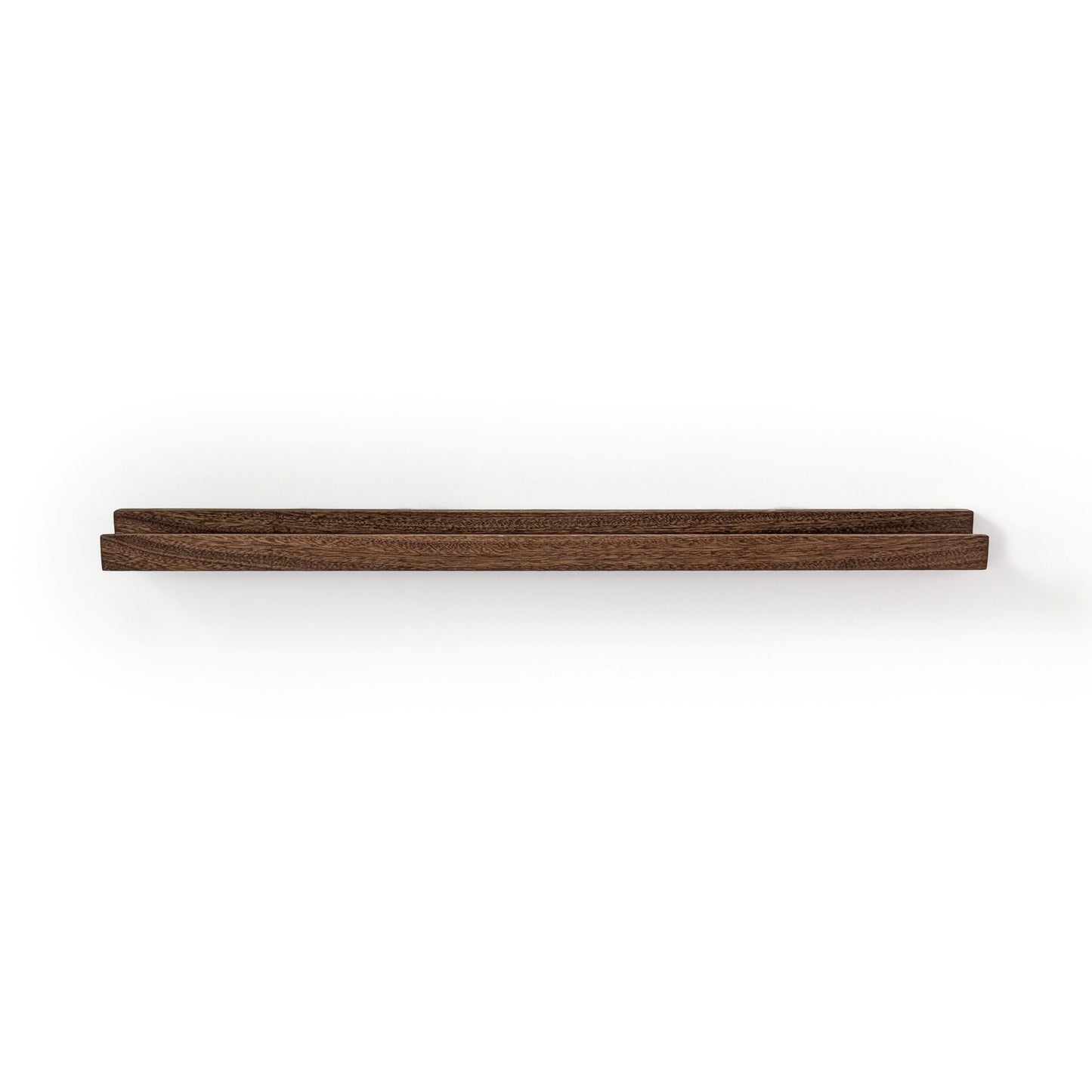 Picture ledge shelf in mahogany with walnut stain on a white wall.