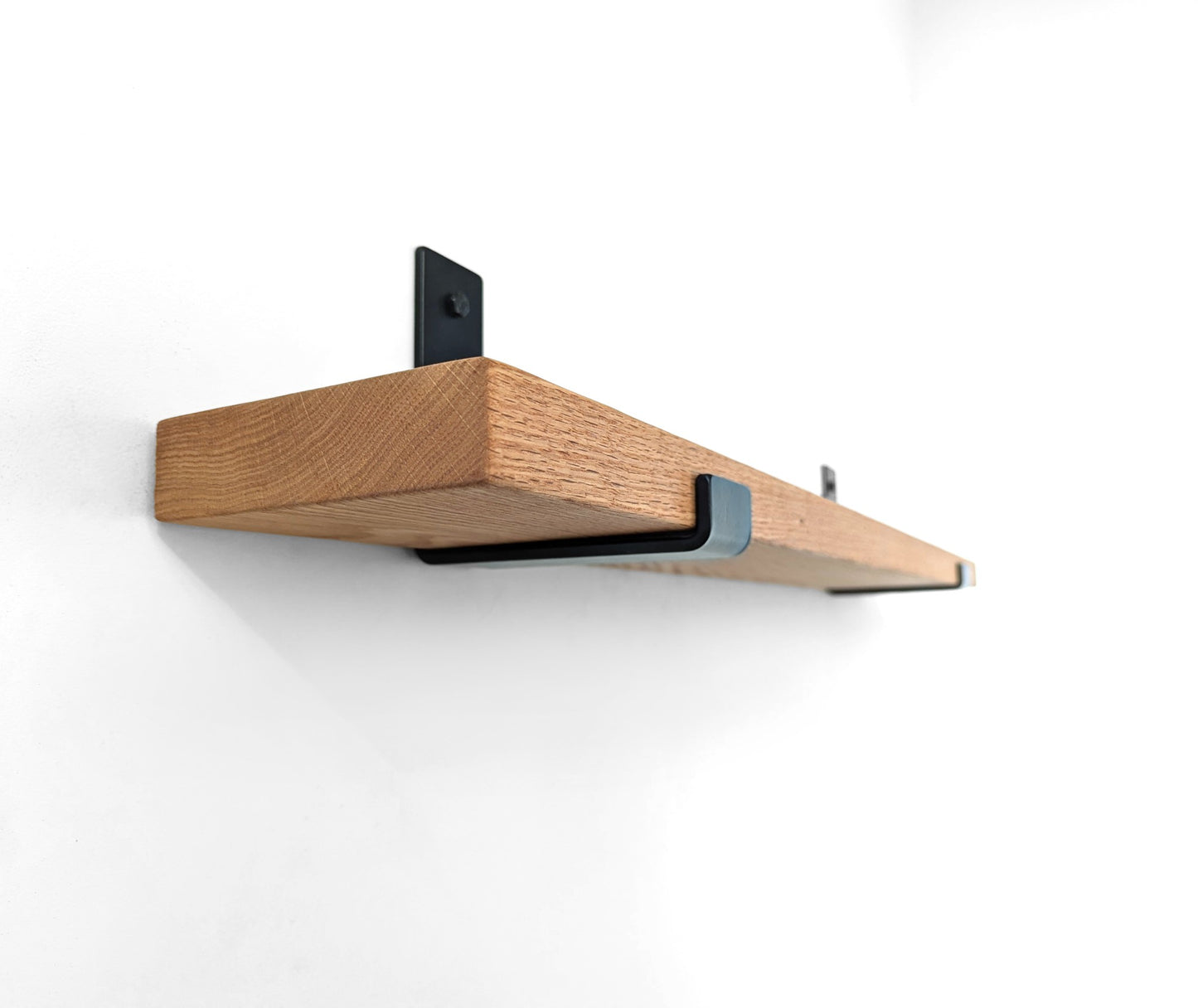 Underside side angle view of a thick oak shelf with J brackets.