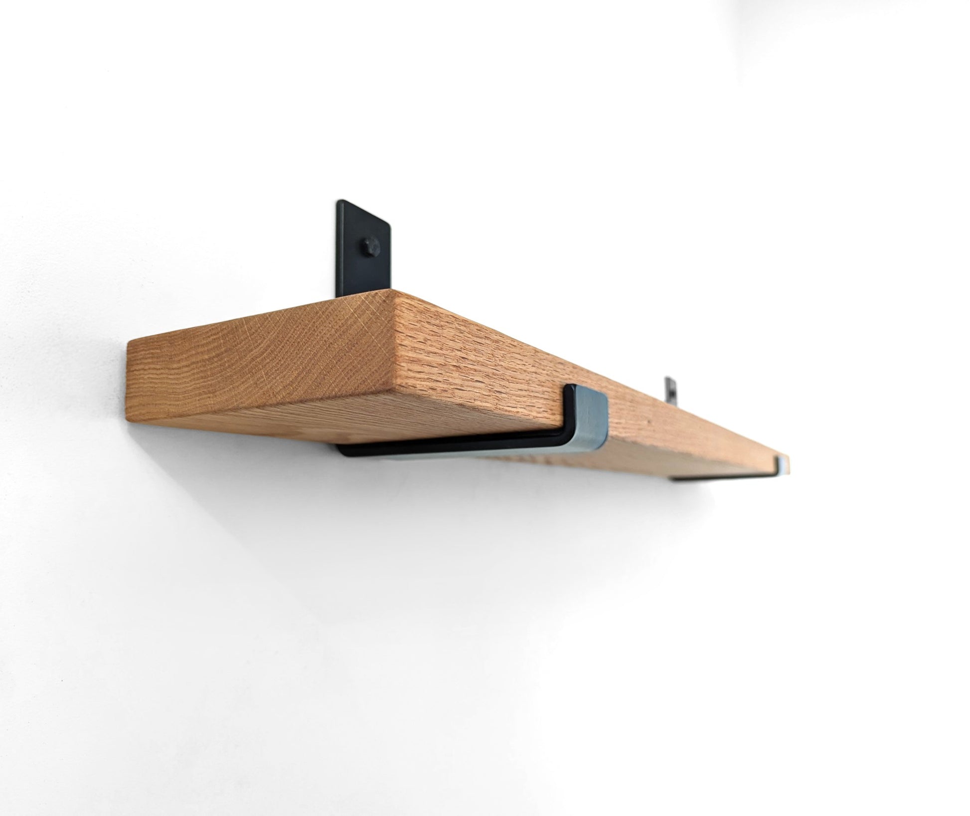 Underside side angle view of a thick oak shelf with J brackets.