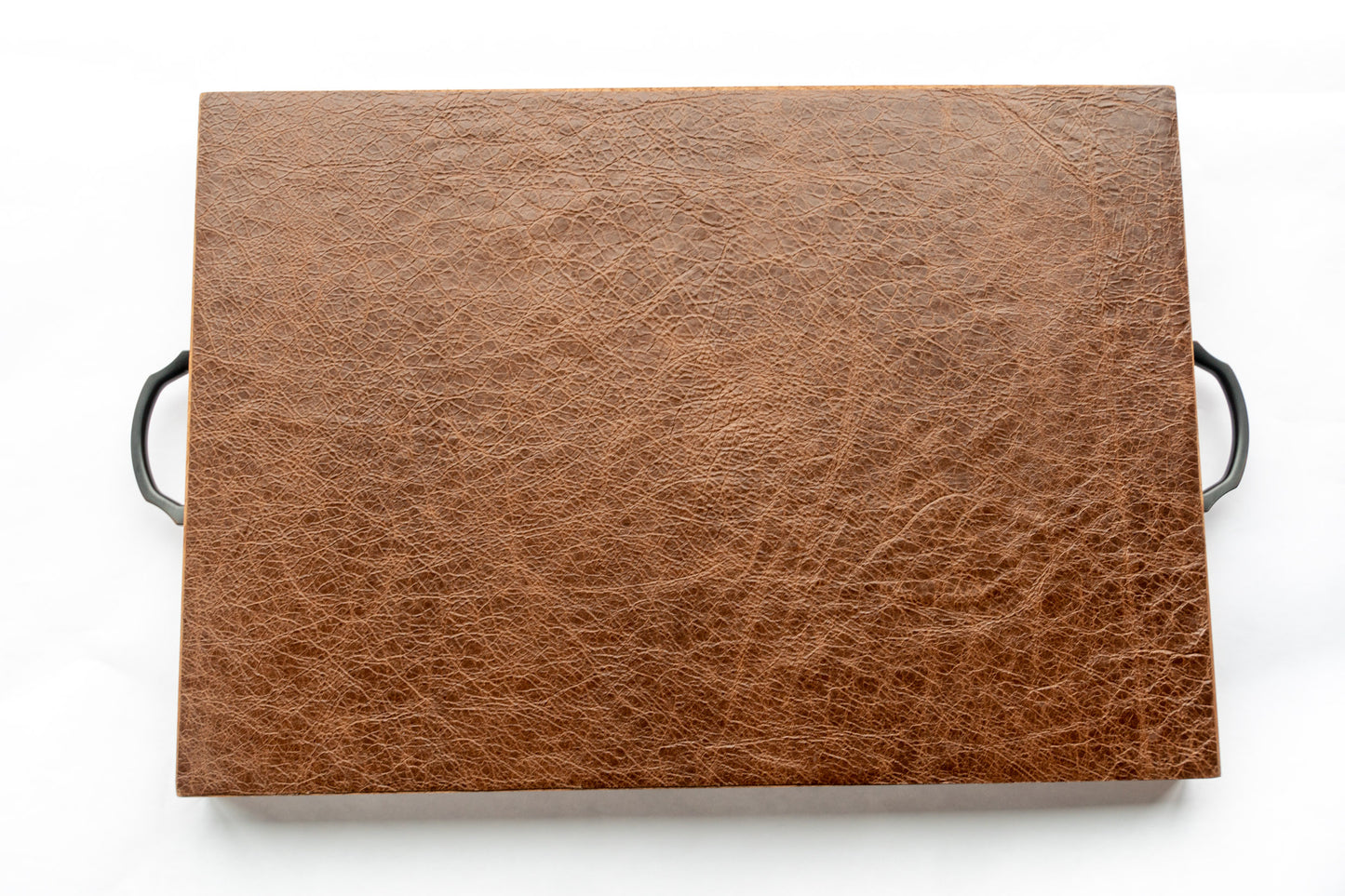 A view of the soft and supple full-grain leather on the bottom of our Luxury Serving Tray. Fine lines reach across the leather and two black handles extrude from either side allowing for safe and secure handling.