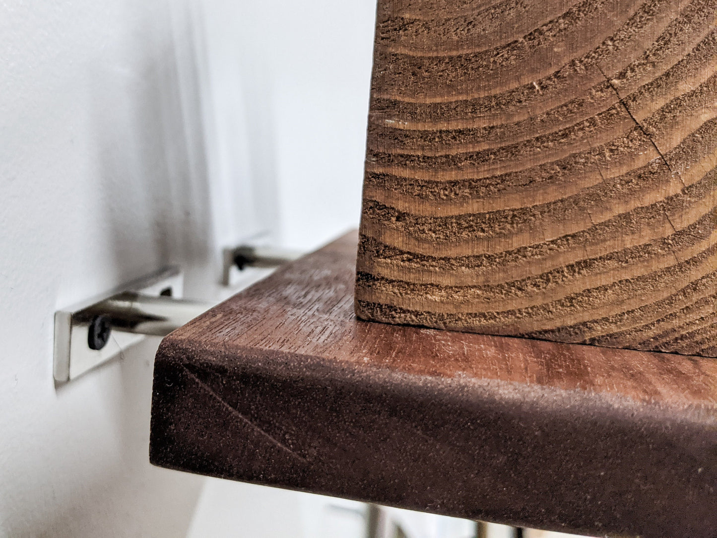 A medium floating shelf is easily installed with brackets. The brackets are silver and secure into the wooden shelf.