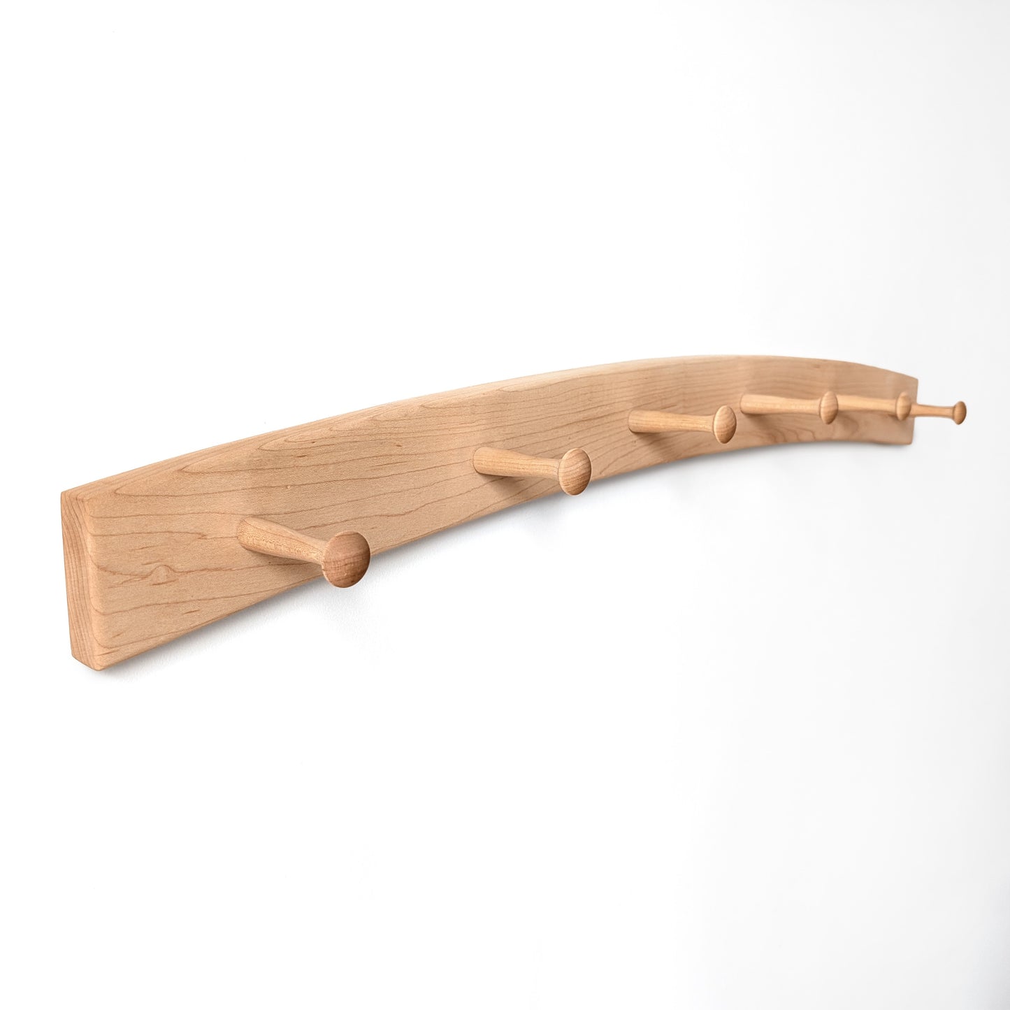 Arched wooden coat rack with six shaker pegs on a white background