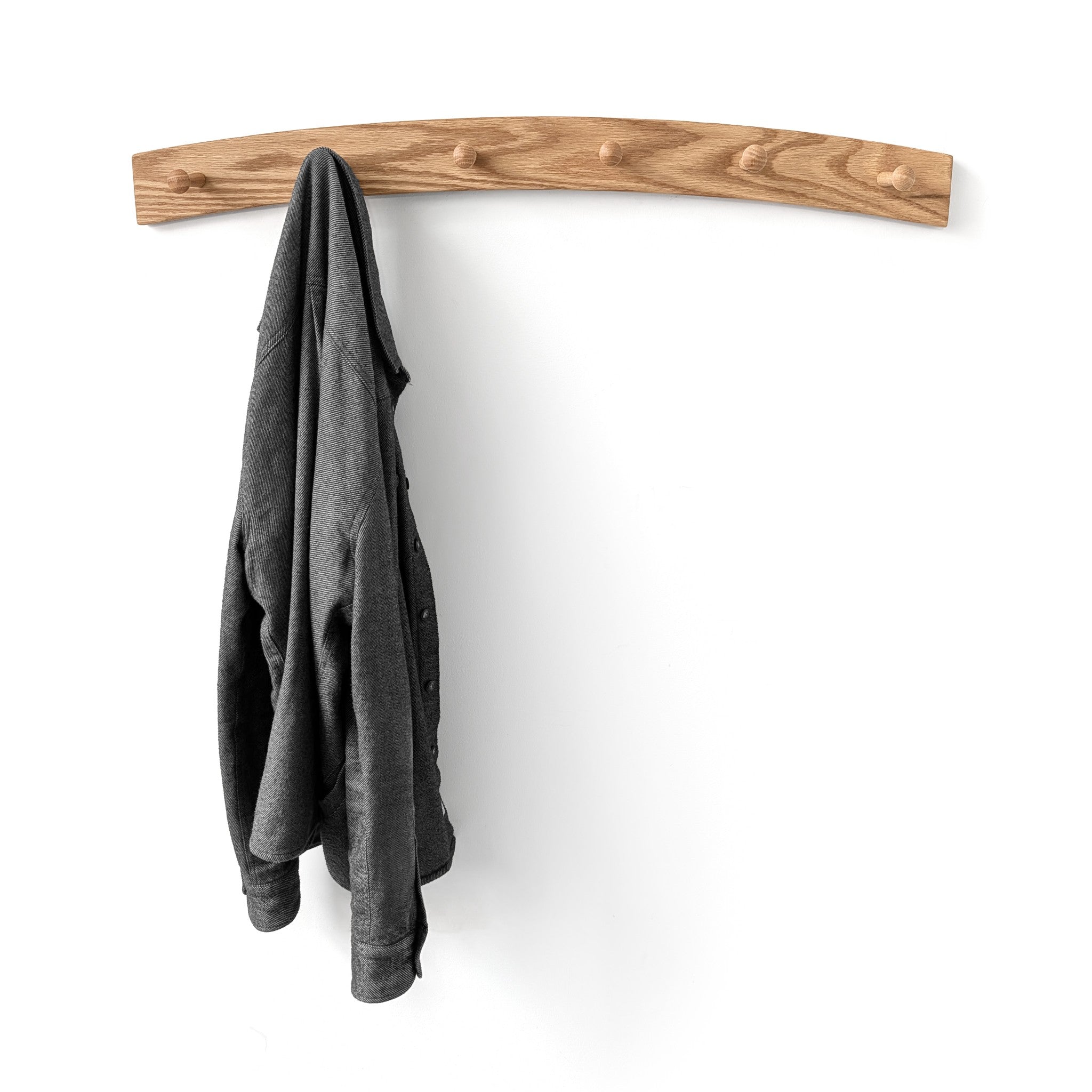 Wood oak coat rack with six pegs holding a gray jacket on a white background