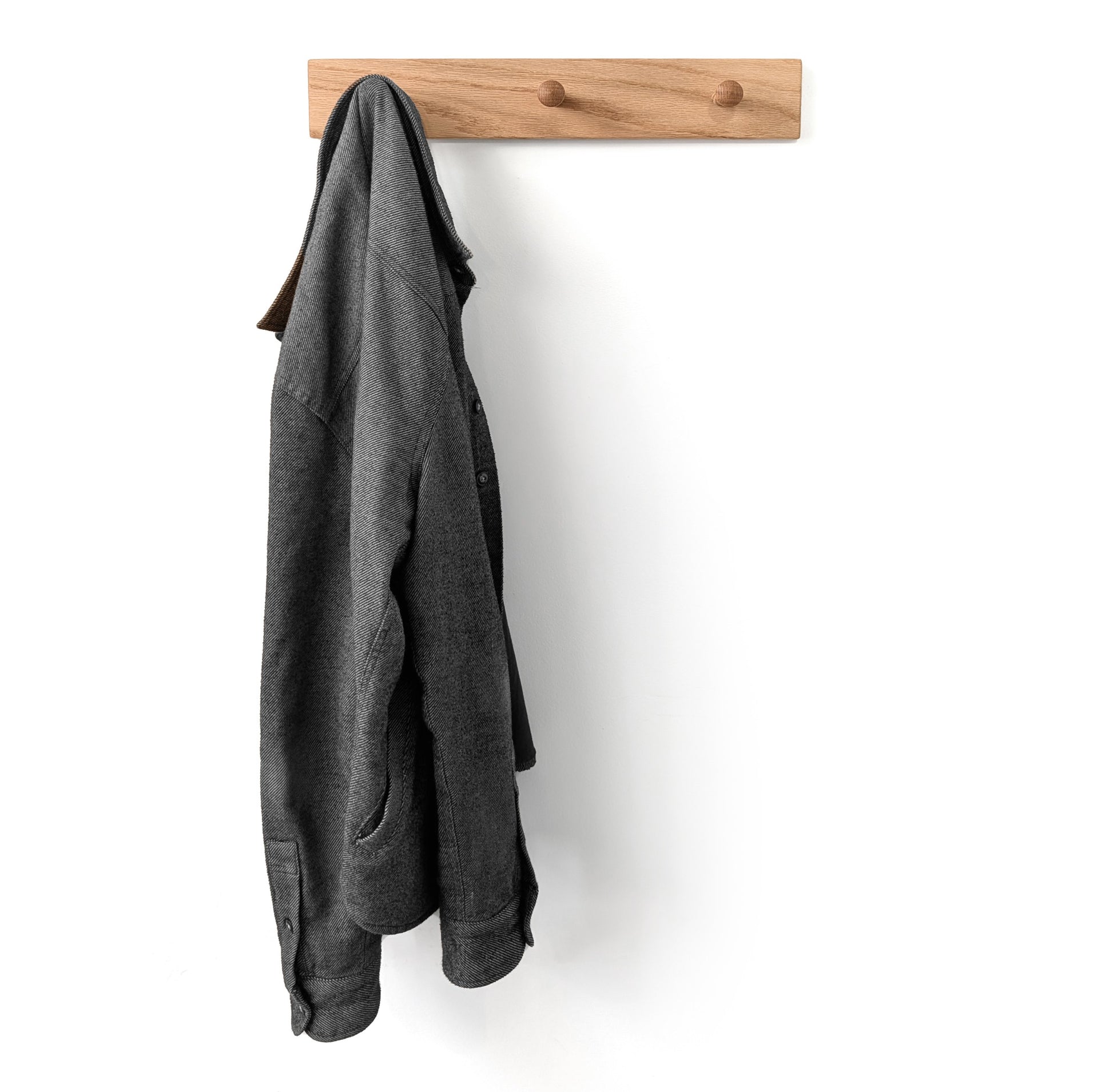 Gray coat hanging on a 3 peg wooden wall hook coat rack against a white background