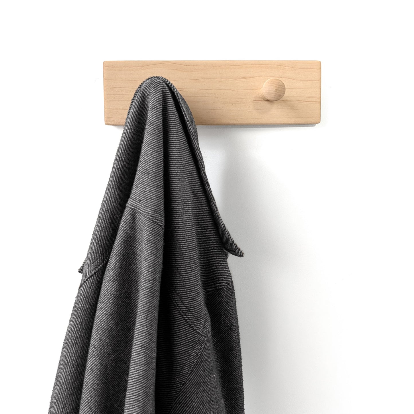 Two peg wooden wall hook with a gray coat hanging on it against a white background