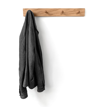 Gray coat hanging on a wooden wall hook against a white background
