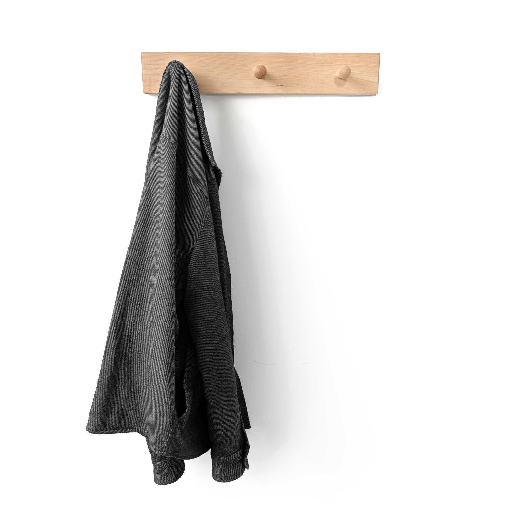 Gray jacket hanging on a three peg wooden coat rack against a white background