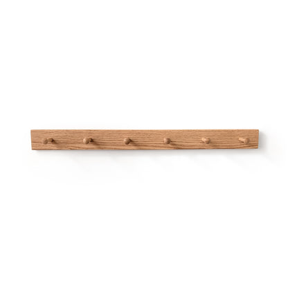 6 peg oak coat rack on a white wall