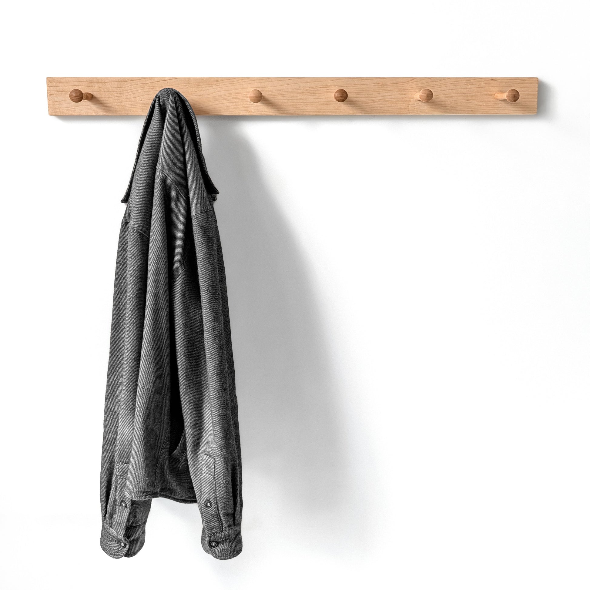 Classic maple wooden coat rack with a gray jacket on a white background, six shaker pegs