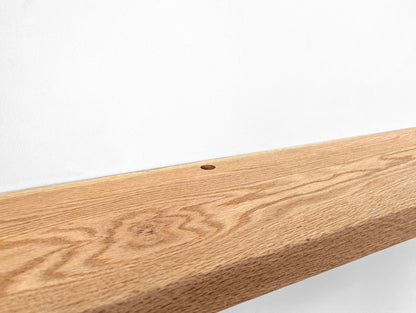 Zoomed in photo of a grommet hole in an oak floating shelf.