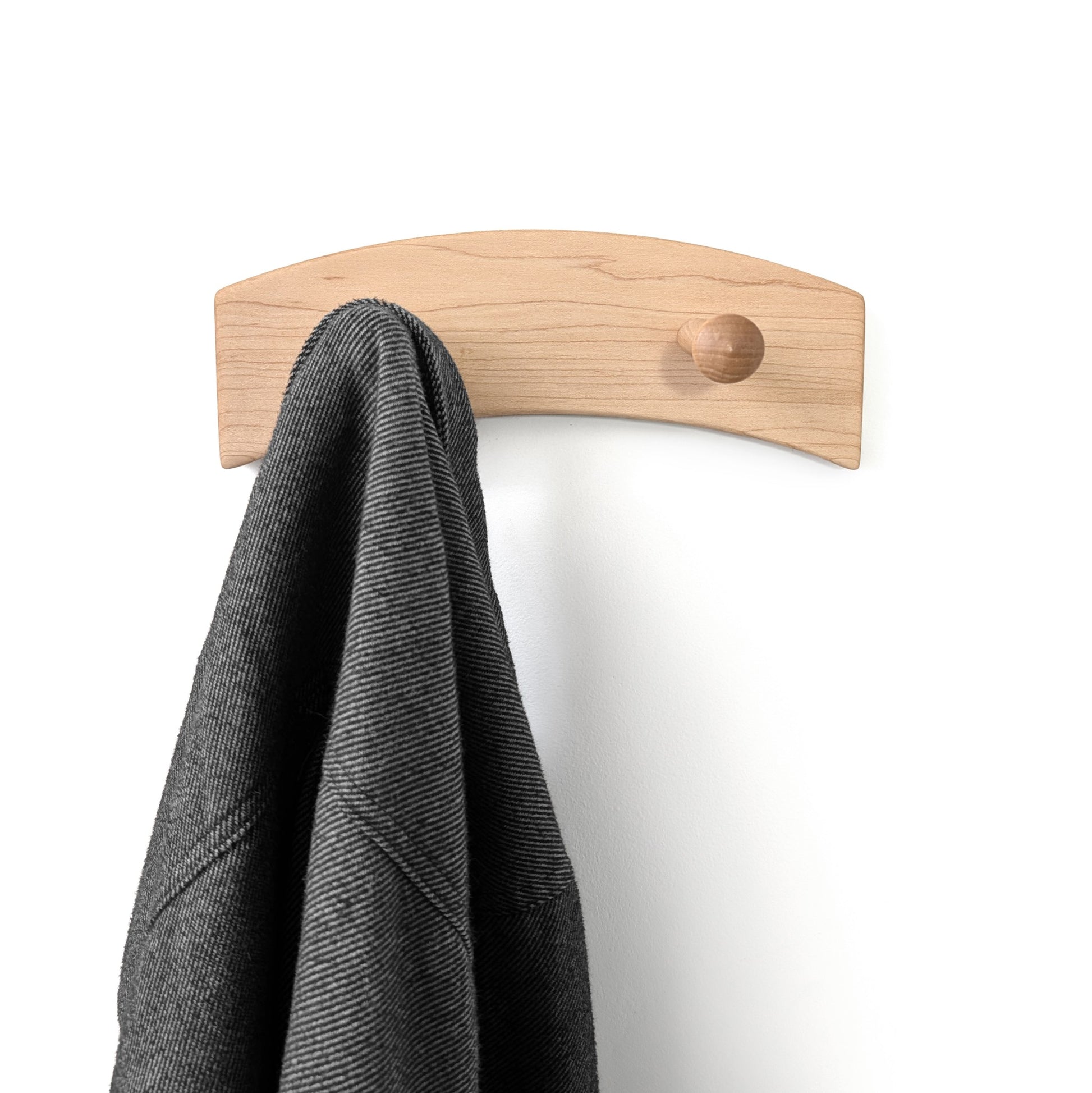 Wooden wall hook coat rack with two pegs holding a gray coat on a white background