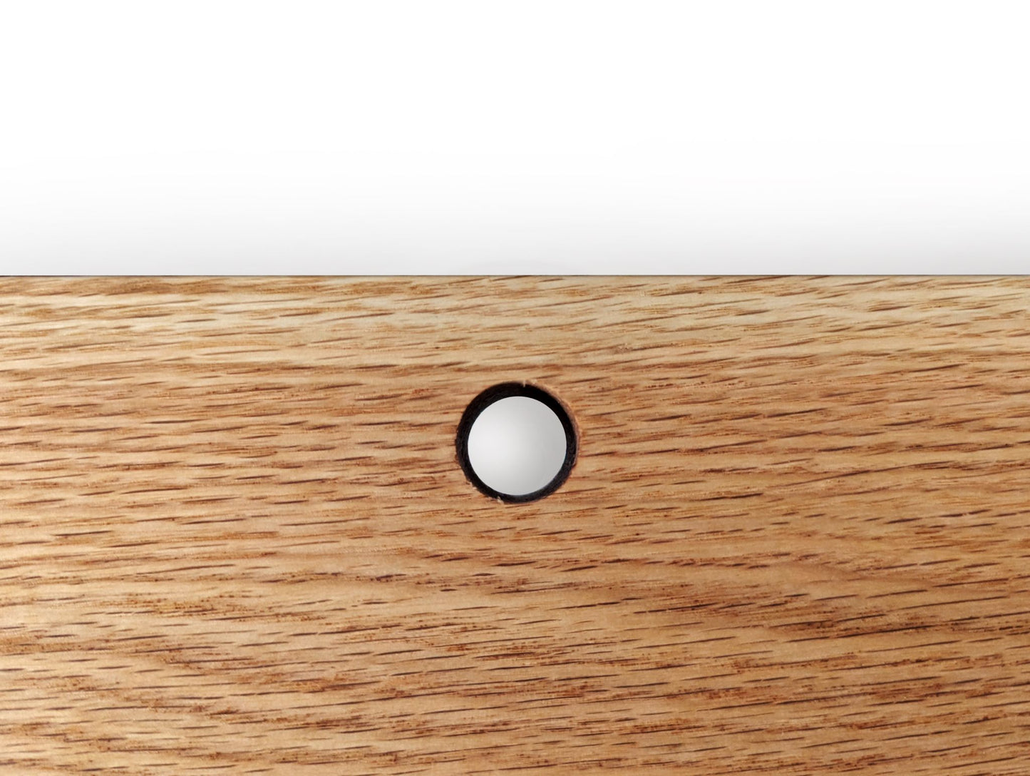 A cord hole in an oak shelf.