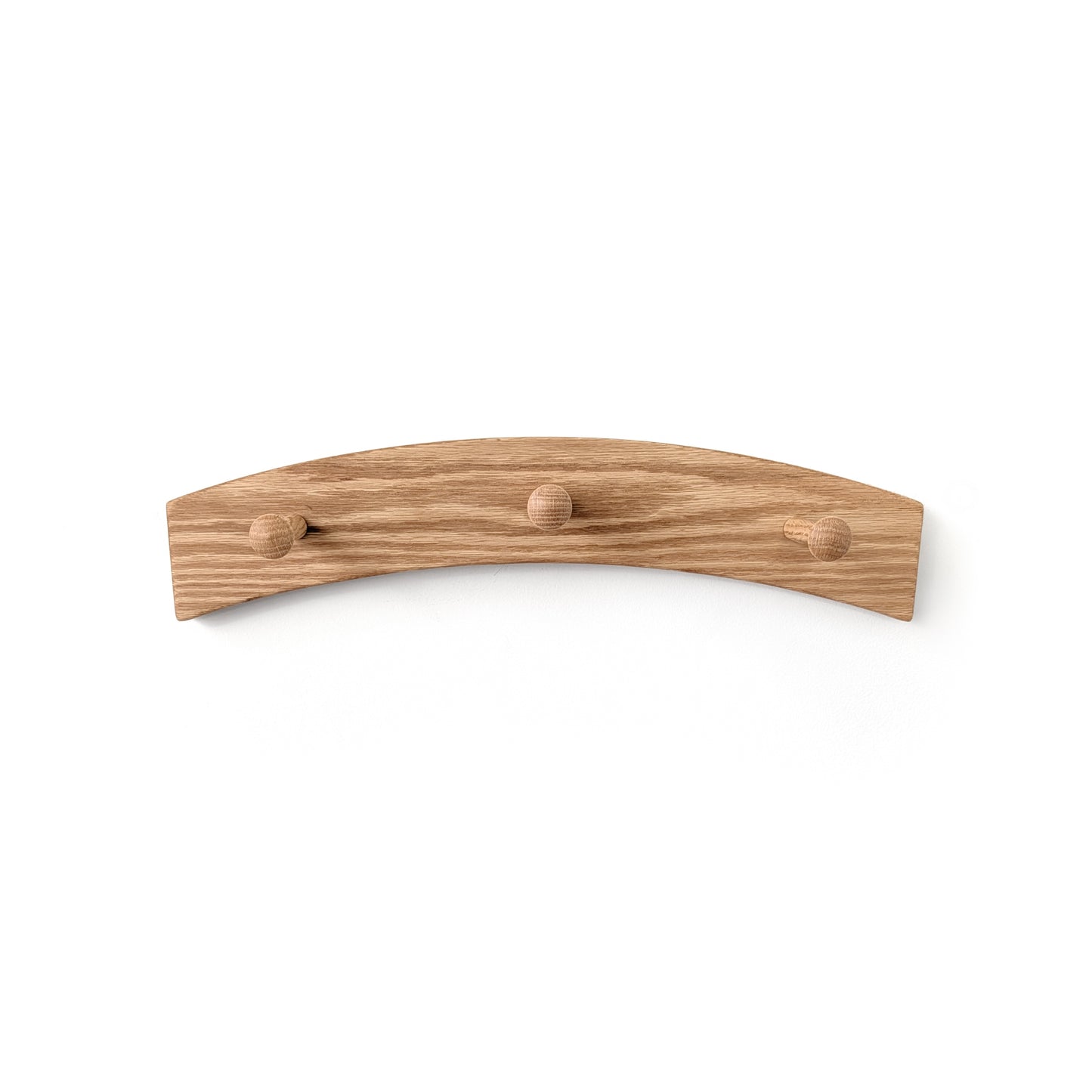Three peg coat rack with an arch design on a white wall