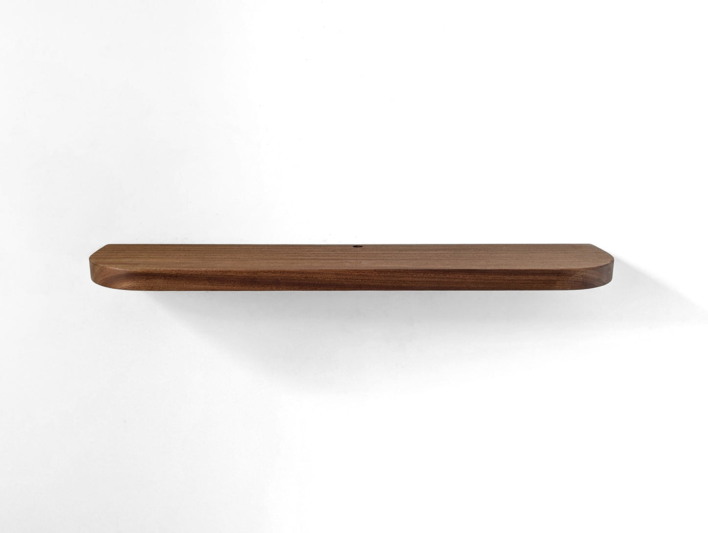 Angled down photo of a mahogany shelf with rounded corners and a grommet hole
