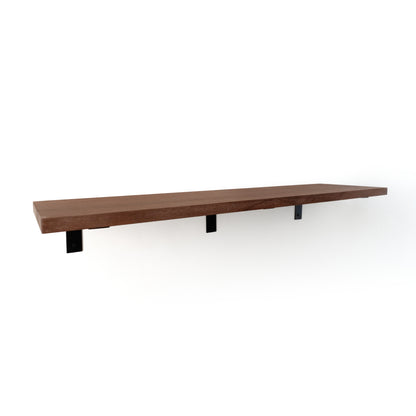 Long wooden shelf with three black L brackets on a white background