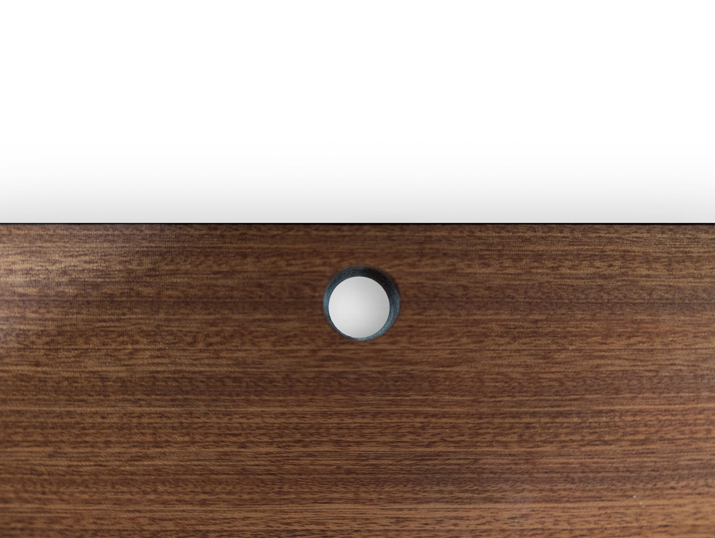 A zoomed in picture of a cord hole in a mahogany shelf.