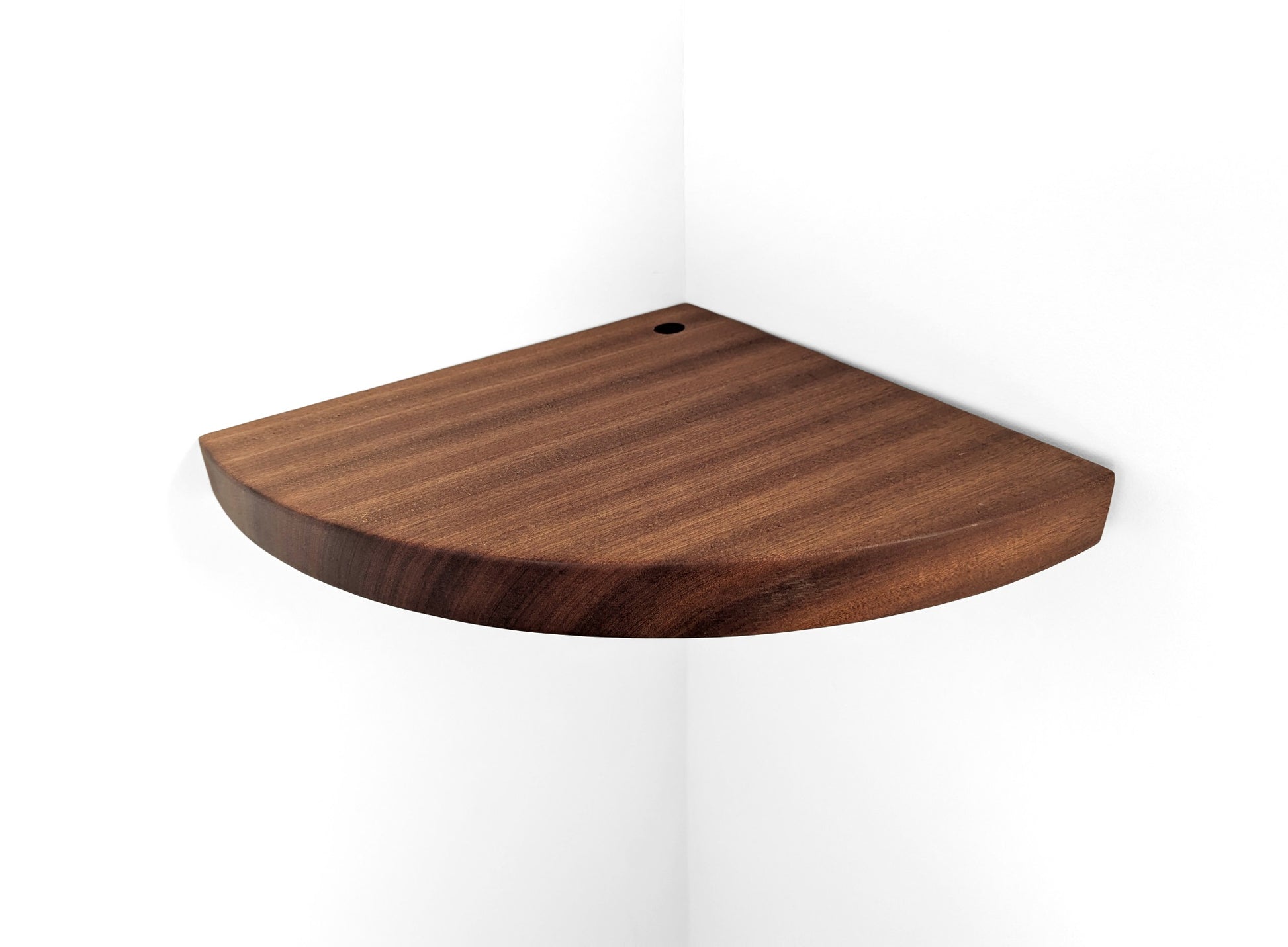 Top view of a cord hole in a thick mahogany corner shelf.