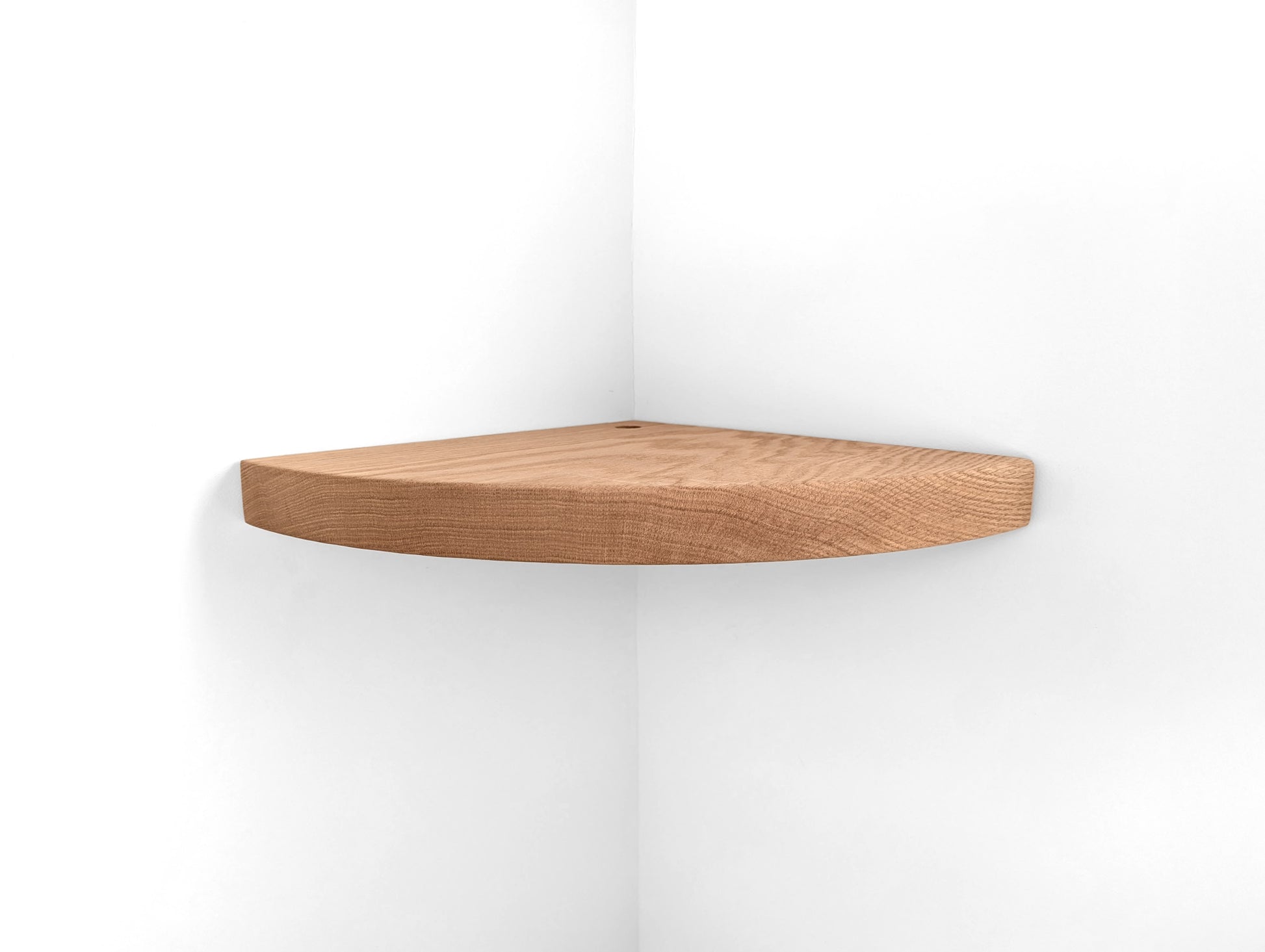 Oak corner floating shelf hangs on a white wall at the corner.