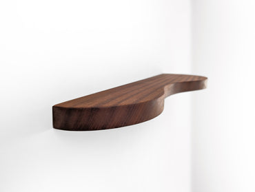 A mahogany double curved floating shelf, photo taken near wall on a sharp angle
