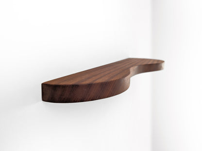 A mahogany double curved floating shelf, photo taken near wall on a sharp angle