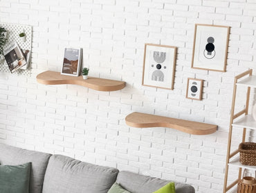 Two double curve thick floating shelves are attached to a wall with decor in a living room.