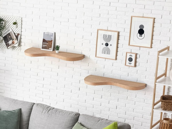 Two double curve thick floating shelves are attached to a wall with decor in a living room.