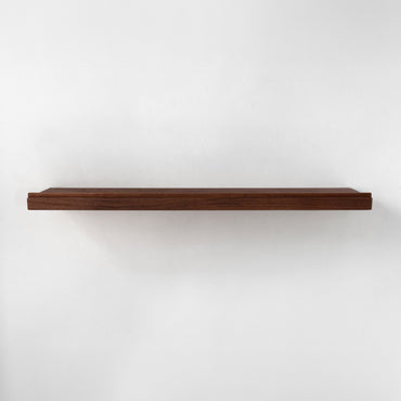 A single long floating shelf made of dark brown wood and a lip on the front, shown horizontally against a plain white wall.