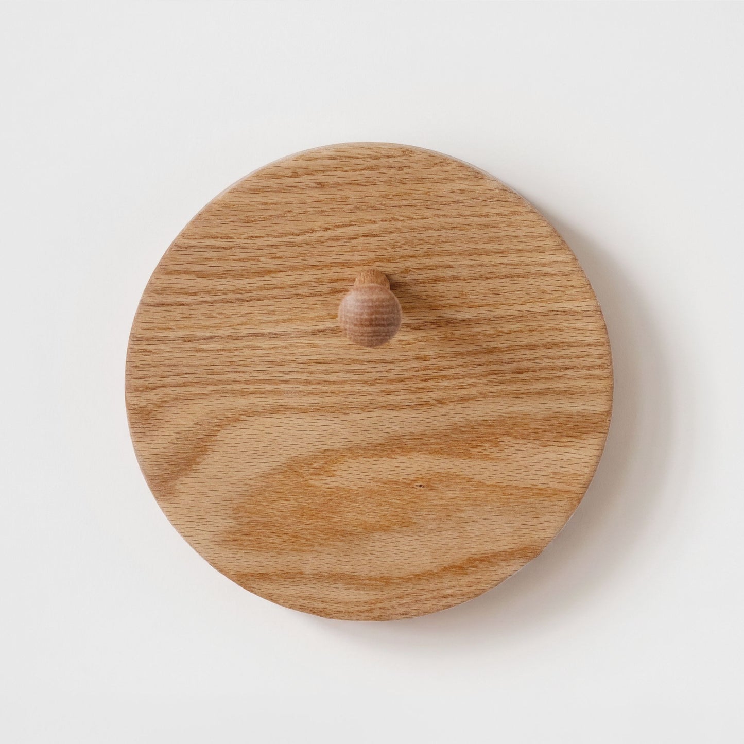 A round wooden hat rack with a small round wooden knob in the center, photographed from the front on a plain white background.
