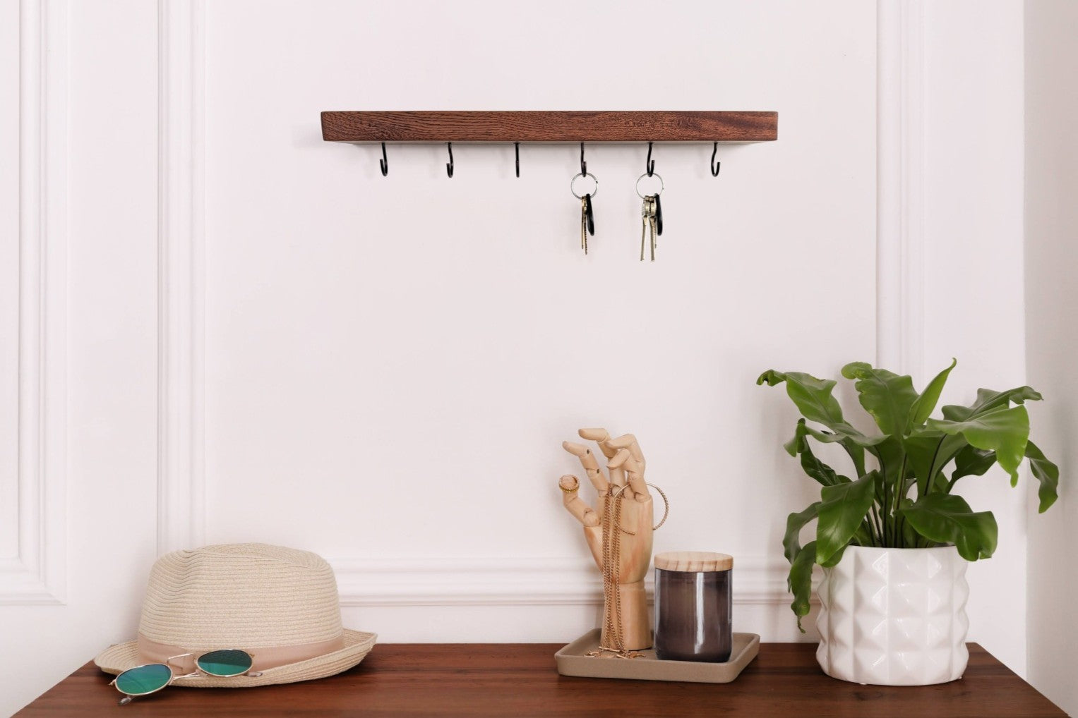thin mahogany key hook shelf installed on a wall with an entry table underneath.