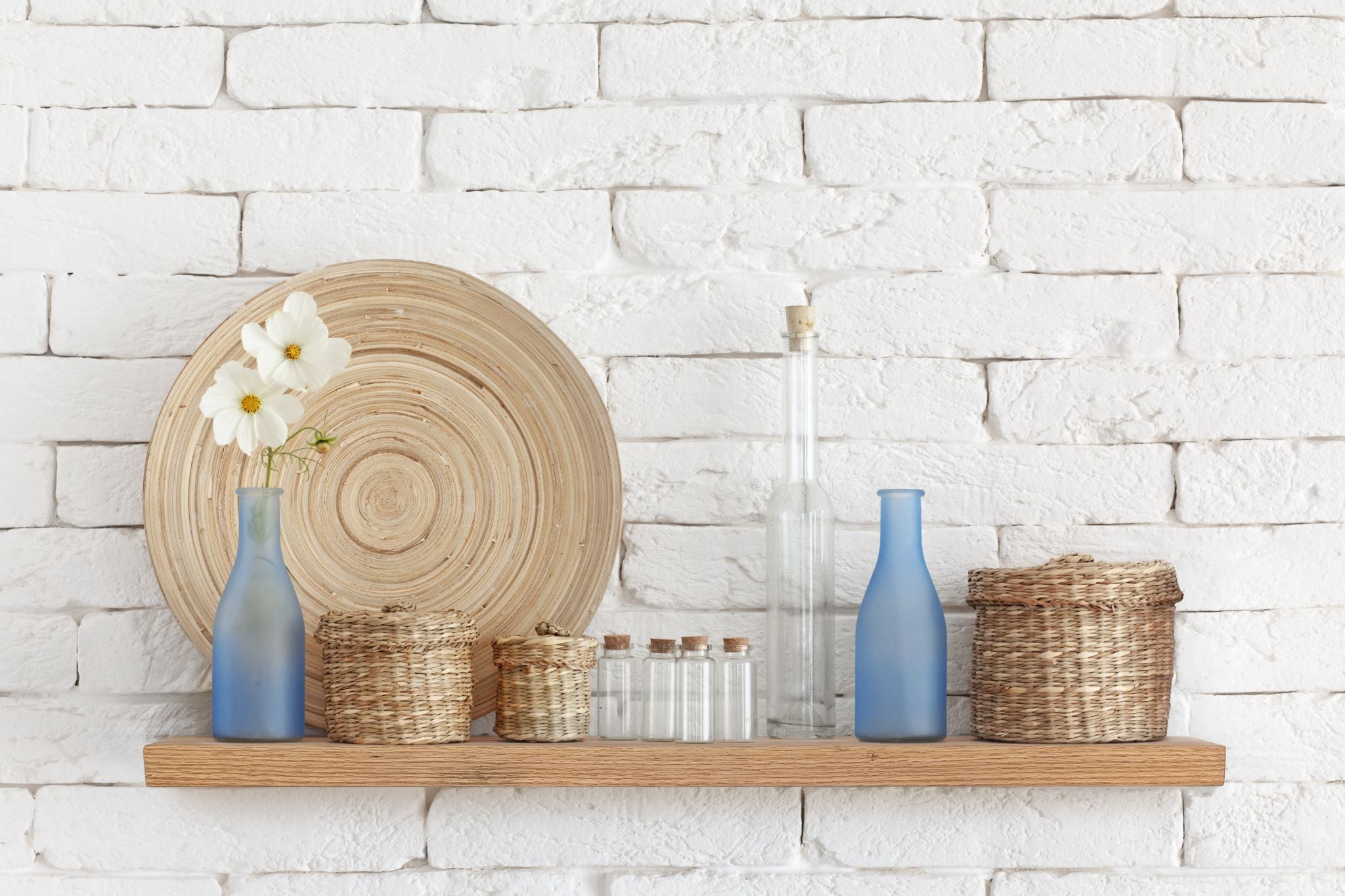 Thick oak floating shelf on a white brick wall with decorative items on the long shelf