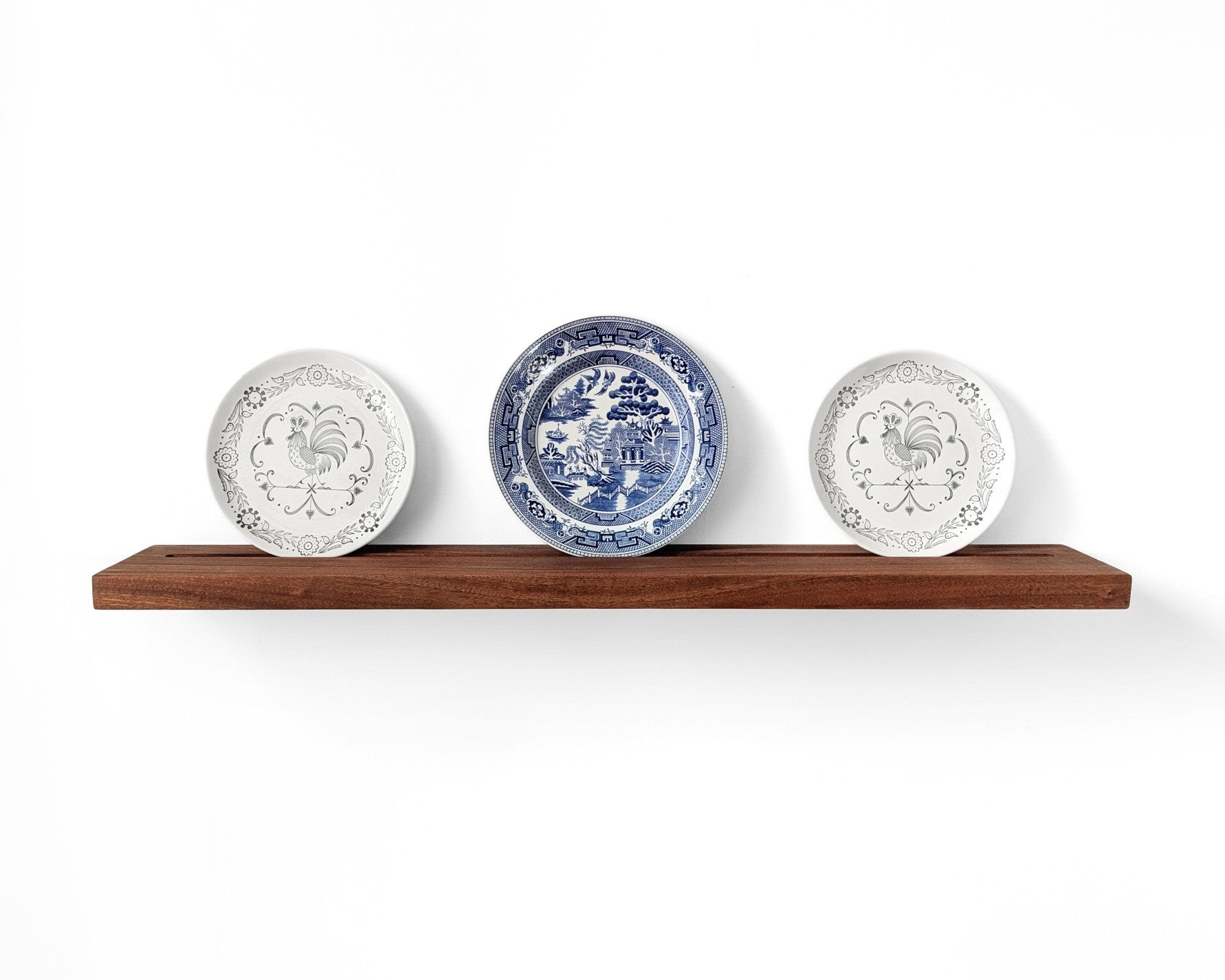 Mahogany plate display shelf with three decorative plates displayed in the groove on the shelf.
