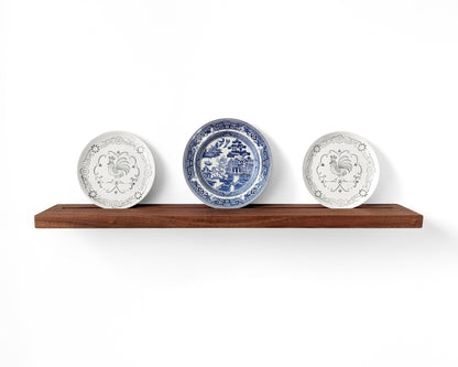Mahogany plate display shelf with three decorative plates displayed in the groove on the shelf.