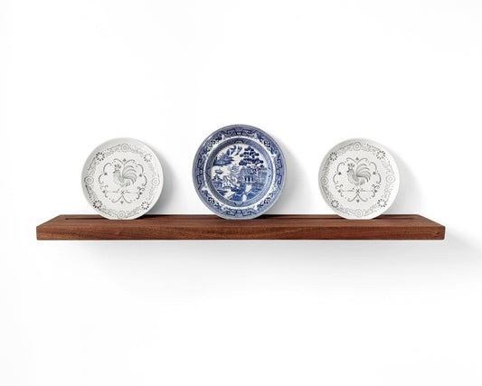 Mahogany plate display shelf with three decorative plates displayed in the groove on the shelf.