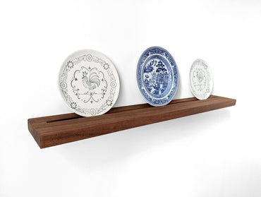 Angled view of the mahogany decorative plate shelf with three plates.