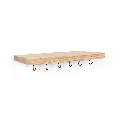 A maple wood floating shelf with five black metal hooks hanging underneath, shown against a plain white background.