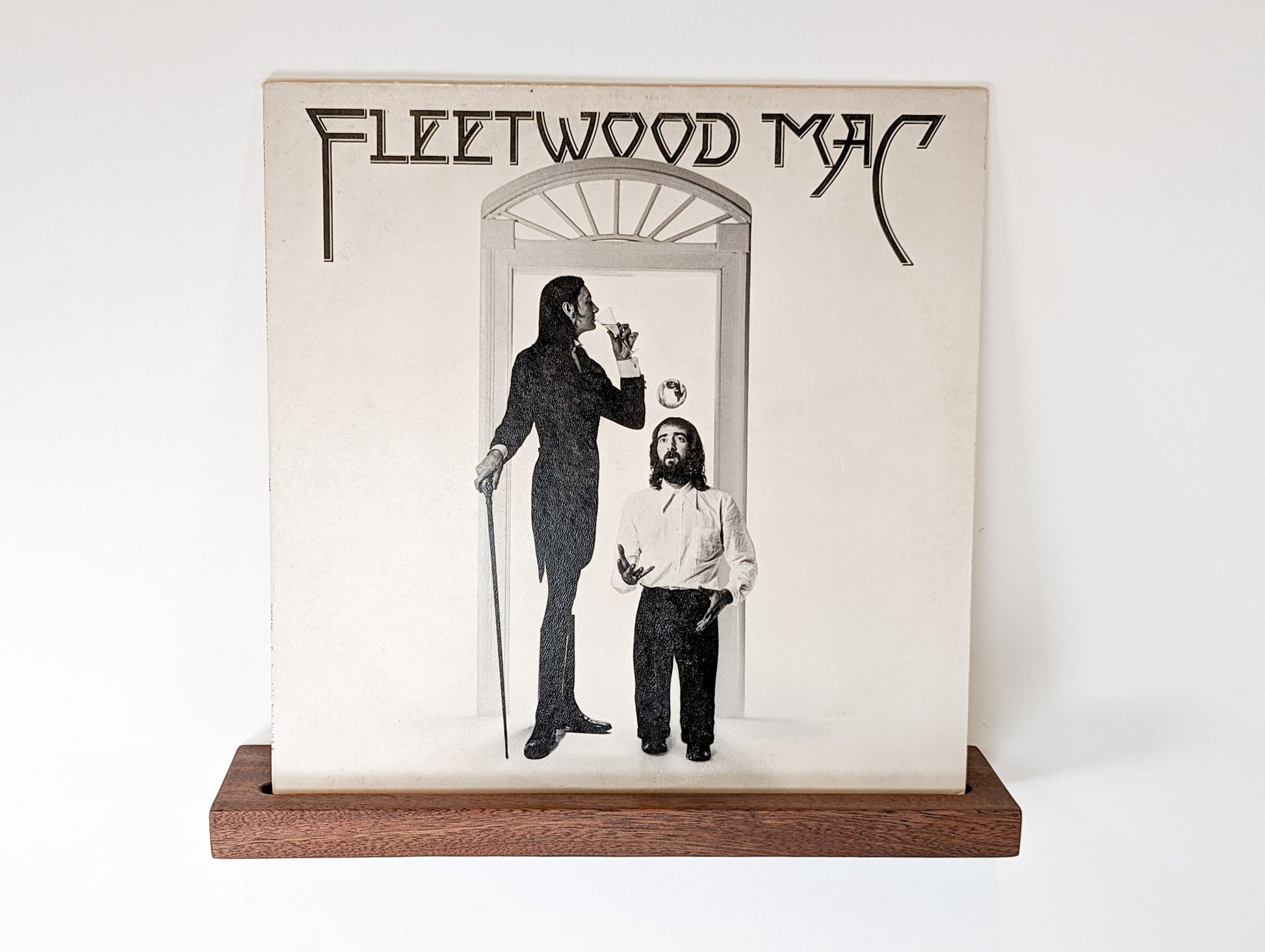 Straight on shot of a mahogany shelf with a vinyl record on top.