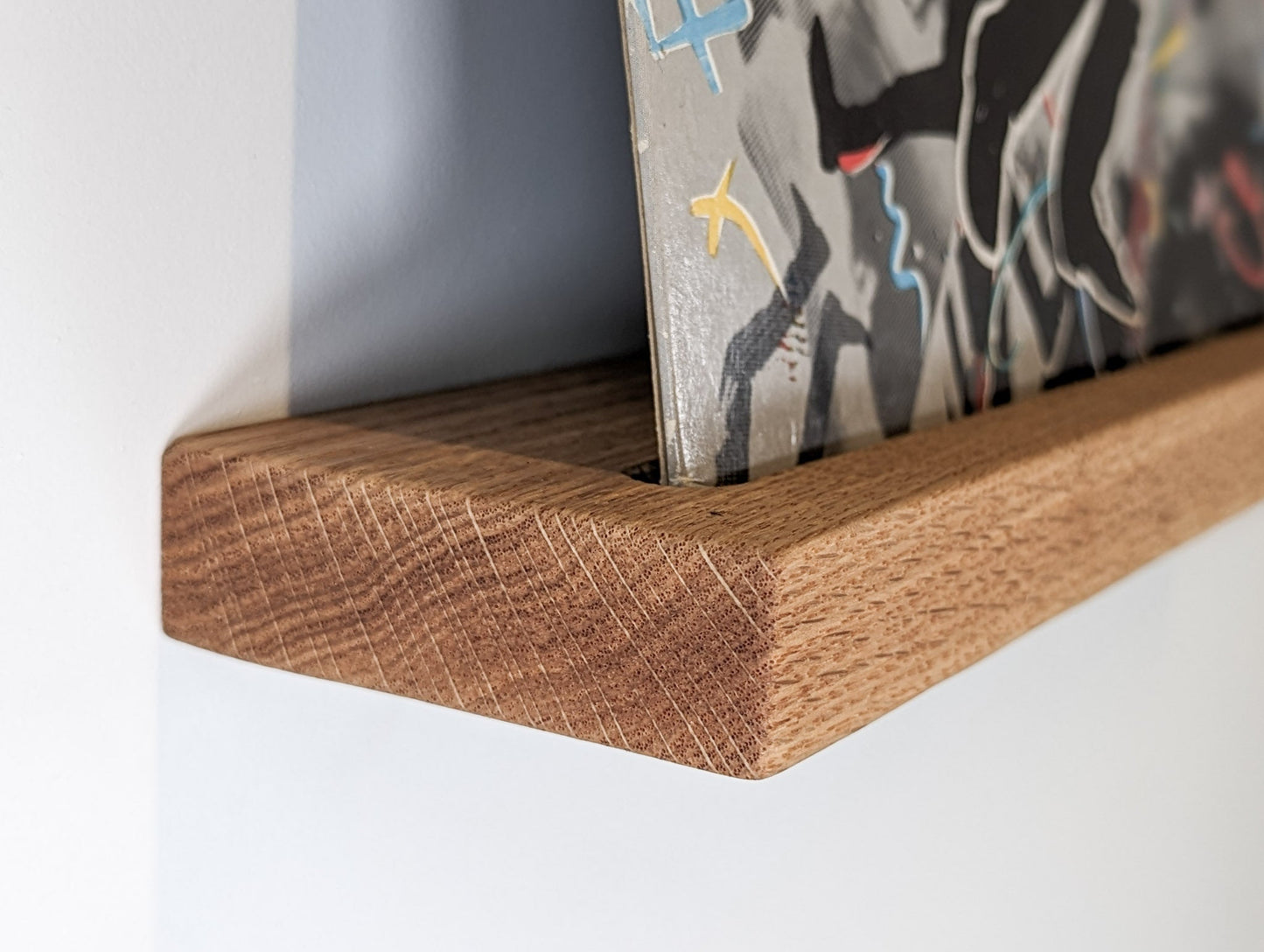 Close up picture of the corner of a vinyl record floating shelf in oak.
