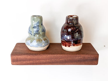 A front view of a mahogany shelf with two vases displayed on top.