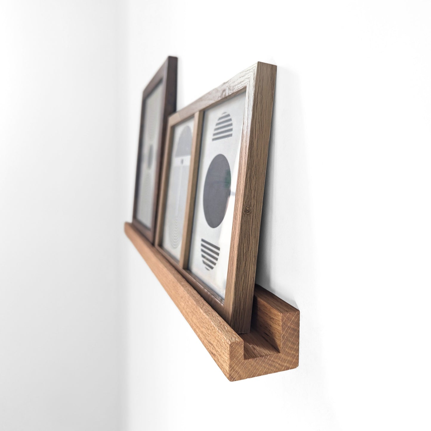 Angled view of an oak shelf for picture frames.