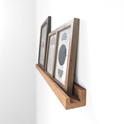 Angled view of an oak shelf for picture frames.