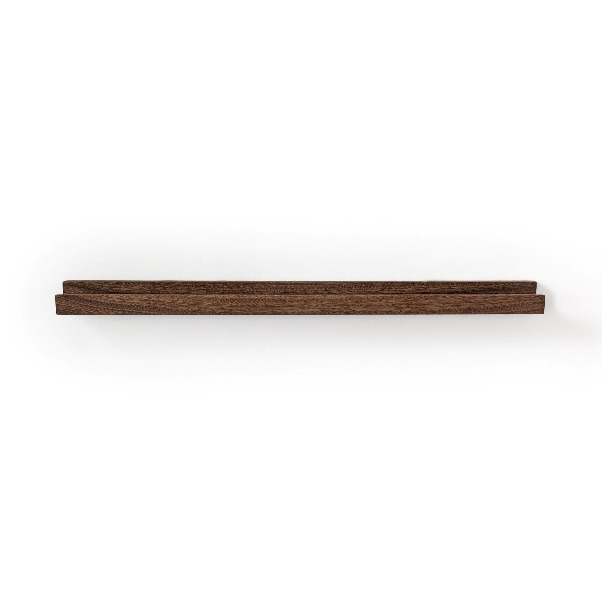 Picture ledge shelf in mahogany with walnut stain on a white wall.