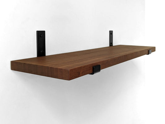 Thick mahogany shelf with steel black powder coated J brackets attached to a white wall.