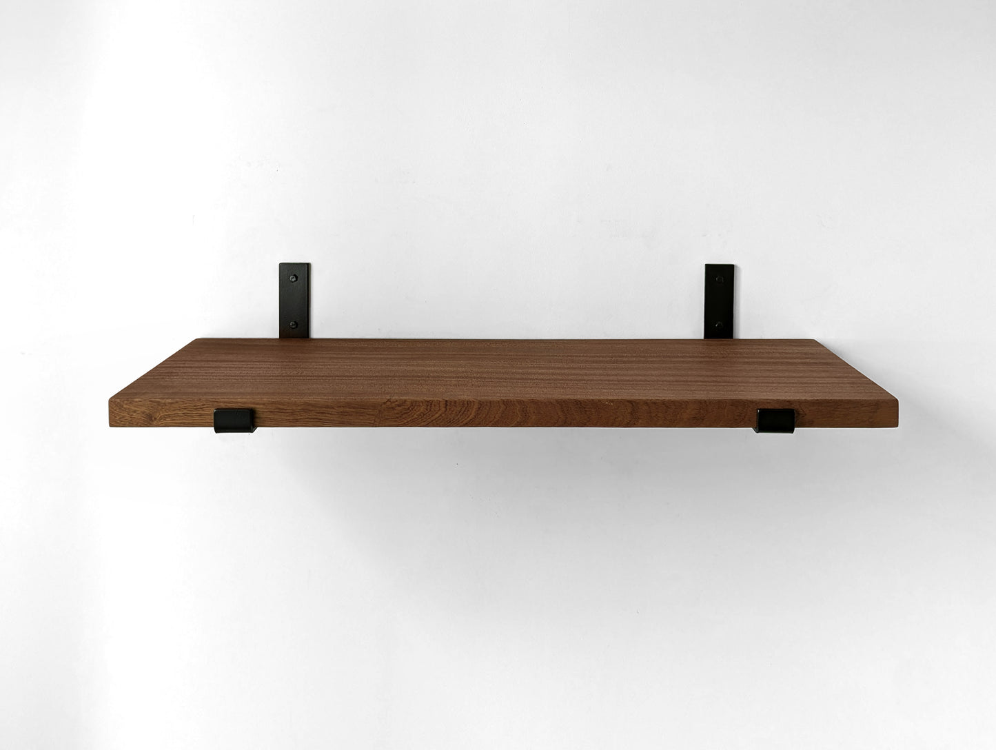 Front view of a large mahogany shelf and two black heavy duty J brackets.