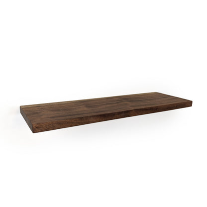 Thick and long mahogany floating shelf with walnut stain on a white wall.