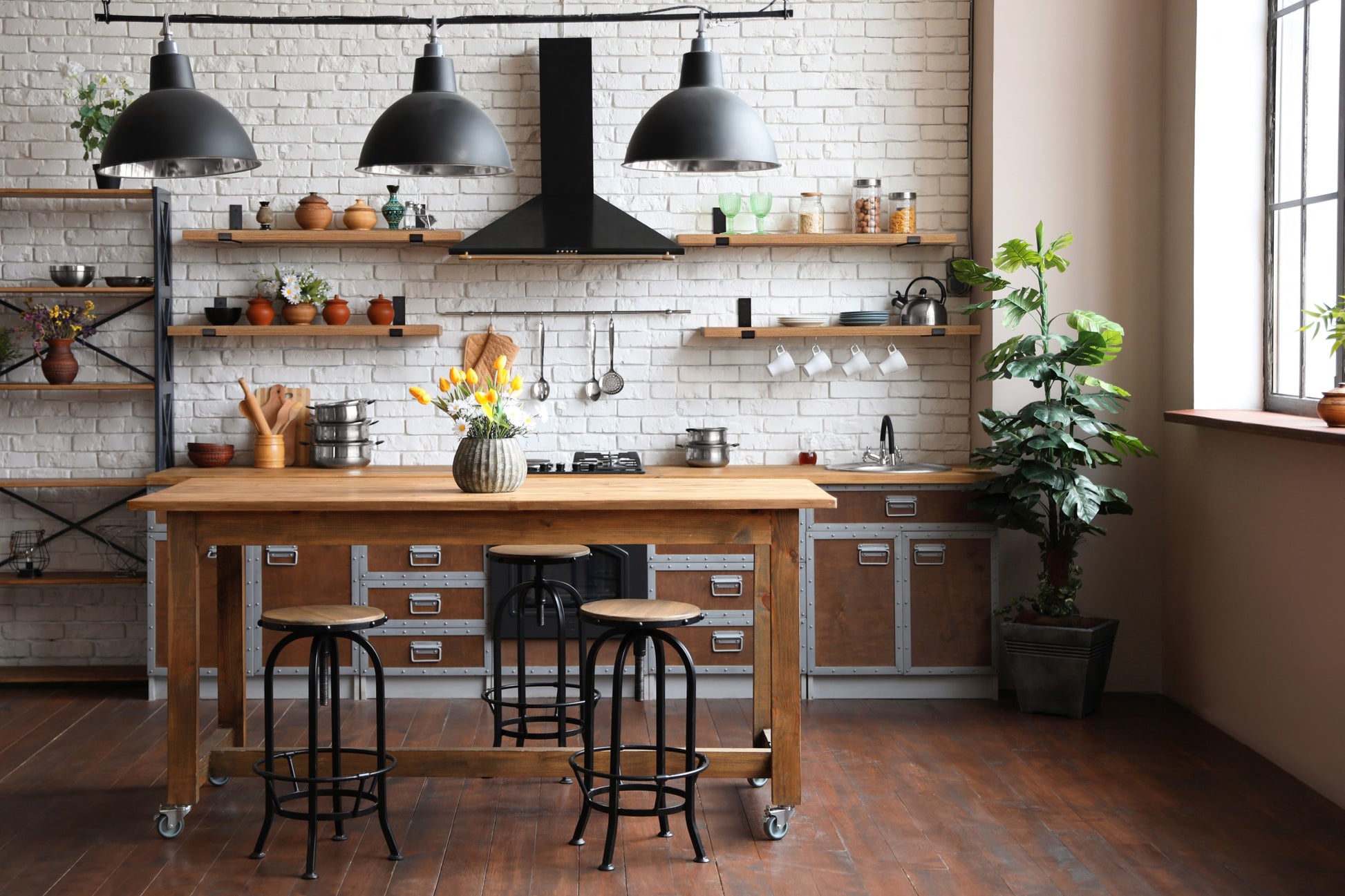 Four thick oak shelves with steel J brackets on a kitchen wall with kitchen items displayed on the shelves. 